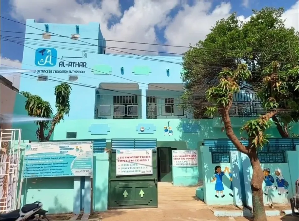 Façade turquoise du Complexe scolaire Al-Athar avec son enseigne, son portail et des personnages peints sur le mur